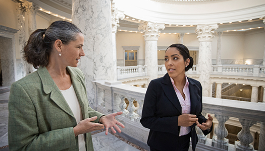 Two women talking to each other while walking together inside a government building