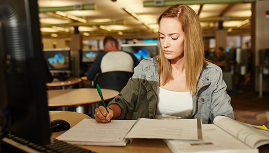 A student sitting in a library and studying