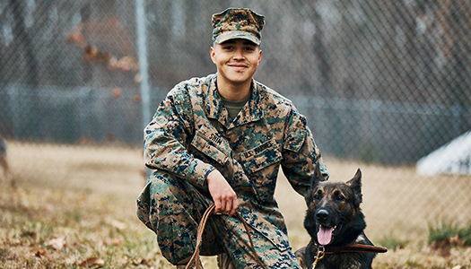 A Marine K-9 handler sitting with a military dog