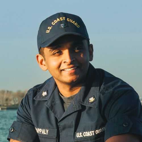 Man in U.S. Coast Guard uniform smiling and facing towards his left