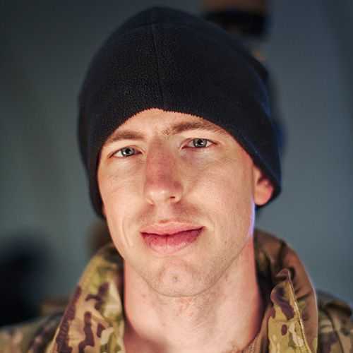 Man in U.S. Army uniform smiling and facing towards his right